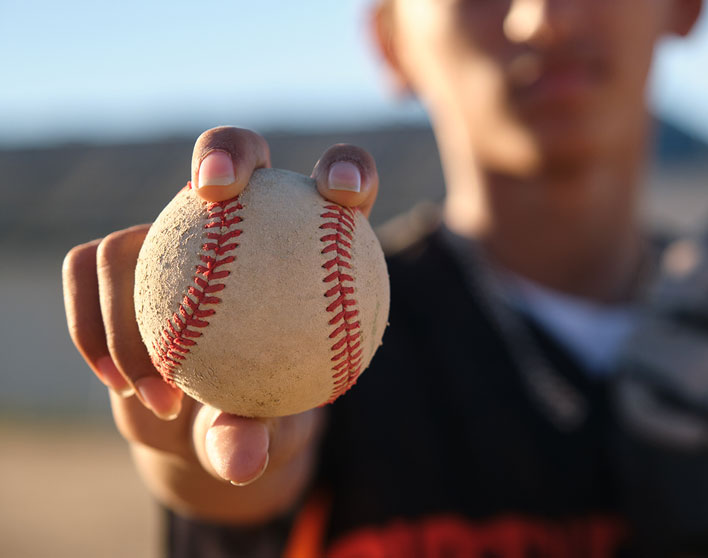 Kid holding up a baseball close up